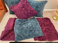Set of three European pillows and three mats in teal blue and dark magenta velvet with raised floral texture, arranged on floor.