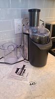 Photo showing the juicer assembled with the juice container and instruction manual on a countertop.