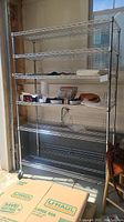 Full front view of large silver metal wire shelving unit on wheels containing various small items.