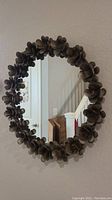 Round wall mirror with decorative metal flower frame on a wall.