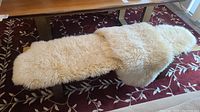 Cream sheepskin bench cover draped on wooden bench, full view