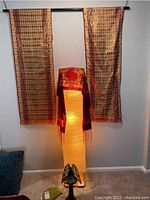 58-inch floor lamp lit with a red-orange scarf draped around it, bronze angel candleholder placed at base