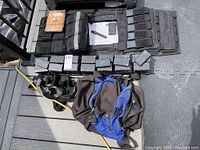 Full layout of MIR weighted vest with attached straps and pockets containing 2-pound weights, blue and black duffel bag, and Iron Yoga DVD case placed on textured floor mat.