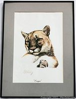 Framed and matted lithograph showing a close-up portrait of a cougar with the artist's hand signature and the title below the image.