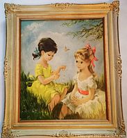Full view of the framed print showing two young girls in a grassy field with butterflies, framed in an ornate gold frame.
