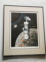 Full framed and matted print showing artwork of a satellite above a textured mechanical planet and stars in background.