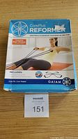Front of the box showing Gaiam CorePlus Reformer product with image of woman using the resistance bands. Box has some wear on corners.