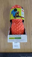 Front view of orange multi-point muscle roller in packaging with visible product label and box details.