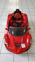 Top view of red LaFerrari ride-on electric toy car sealed on tiled floor, showing front hood and seat.