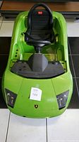 Front view of green Lamborghini kids ride on electric car, showing single black seat, steering wheel, and Lamborghini emblem on the hood.