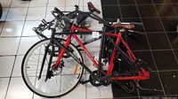 Four Daymak Vermont 36V e-bike frames with some attached components including handlebars and seats, positioned on tiled floor