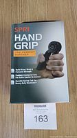 Front view of SPRI Hand Grip box showing product name and features like building hand, wrist, forearm strength, padded contoured grip, and durable spring coil resistance.