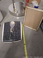 Photo of the vintage frame and bathroom scale together for size reference showing the scale's black and white marbled platform next to an 8x10 frame.
