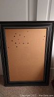 Front view of large cork board featuring light brown cork surface and dark wood frame with silver inset lines.