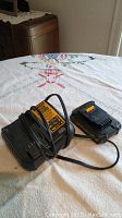DeWalt 20V lithium ion battery and charger with power cord on table with decorative cloth