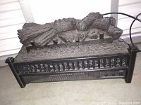 Front view of electric fireplace heater designed to simulate burnt logs, with control switches on the front panel.