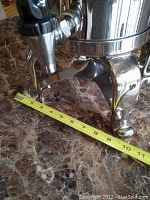 Close-up of the metal stand feet with measuring tape showing approximately 10 inches width between feet on the stand.