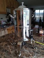 Full view of the silver plated insulated coffee urn on stand with lid in place, showing overall urn design and handles.