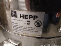 Close-up photo of HEPP brand label on urn with safety information and serial number 1001 dated 06/05.