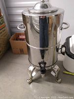 Front view of the large silver plated insulated urn showing spigot, side handles, lid, and curved legs