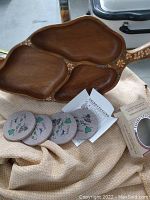 Photo showing the four round ThirstyStone coasters with Hawaiian theme art alongside the wooden tray with three sections.