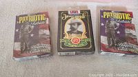 Three unopened decks of playing cards: two Patriotic Tribute decks and one Jack Daniels Gentlemen's deck.