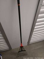 Full view of the heavy duty garden rake with long black handle and adjustable tine spread mechanism.