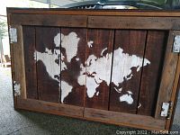 Front side of wooden cabinet showing hand-painted world map on rustic vertical wood slats with nails and hinges visible