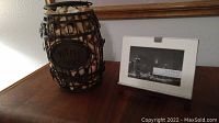Wire barrel filled with wine corks and wooden photo frame on a surface.