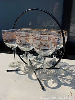 Set of six vintage drinking glasses with metal holder shown together.