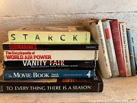 Photo showing stack of 6 books including 'Starck', 'Submarines', 'The Encyclopedia of World Air Power', 'Vanity Fair', 'The Movie Book', and 'To Everything There Is a Season'.