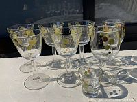 Set of eight stemmed glasses and one small glass with mid century modern atomic design featuring gold and orange circular patterns