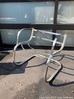 Front angled view of vintage chrome chair frame showing tubular construction and armrest shape.