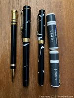 Top view of the vintage Parker black and white fountain pen, mechanical pencil, and two ink cartridge containers on wood background.