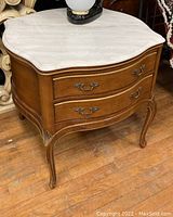 Full front view of two-drawer side table with marble top on wood floor