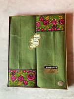 Top view of the two green Irish linen towels with a vibrant floral border, still in original packaging.