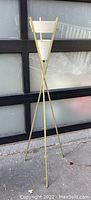 Full view of lamp showing brass tripod base and white perforated shades