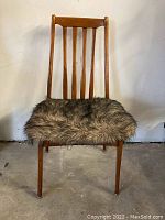Front view of the vintage wooden dining chair showing vertical slatted backrest and faux fur cushion seat.