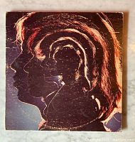Front cover of album with artistic layered profiles of band members in red and black tone, showing wear and edge damage.