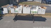 Wide shot of multiple boxes on table showing bottles of cleaning supplies, some with labels visible