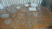 Full view of the entire lot spread out on table showing multiple glass ovenware pieces including casseroles, pie plates, small bowls and juicer.