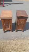 Photo of two matching antique wooden nightstands shown from front, each with two drawers and brass handles, placed on pavement outdoors.