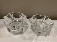Photo showing the pair of clear glass bowls from Orrefors Sweden with geometric wavy edges on a white surface.