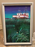 Front view of the framed acrylic painting showing boats on shore with vibrant green foliage and a blue sky.