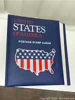 Blue hardcover stamp album with USA map in stars and stripes design on front cover.