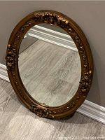 Full view of vintage oval mirror with gold gesso frame showing floral detailing.