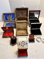 Top view showing multiple open boxes of different materials and designs including a lined box with gold-colored clasp, a wooden box, and a mirrored jewelry box.