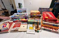 Multiple family games, puzzles, and game books displayed on table