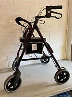 Photo of Merits walker in red and black, showing front and side views with seat, brakes, and storage bag beneath.