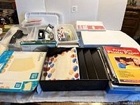 View of assorted office supplies including packs of notebook paper, file folders, stapler, tape, scissors, and photo paper